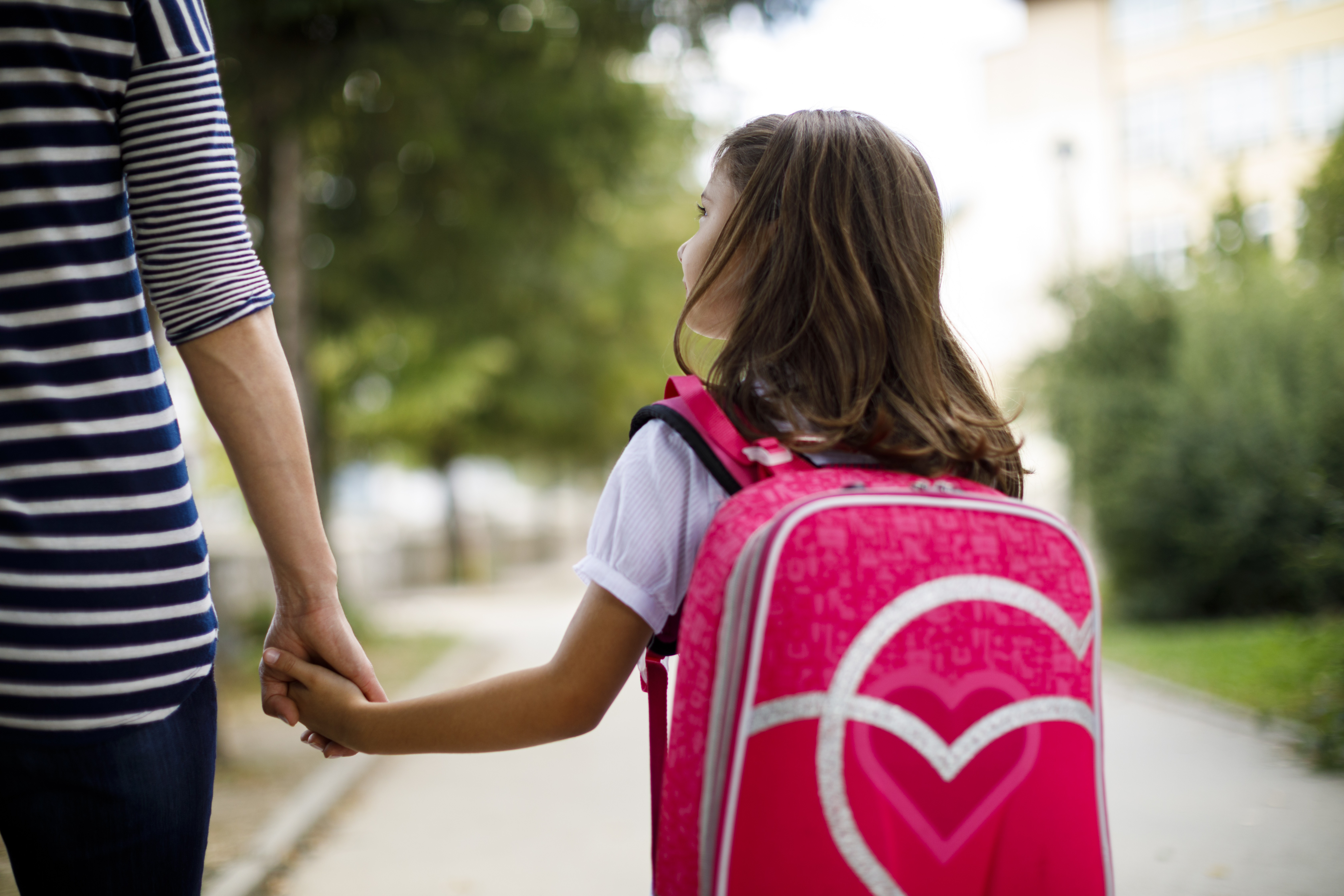 fille de dos avec un sac à dos rose, tenant la main de sa maman