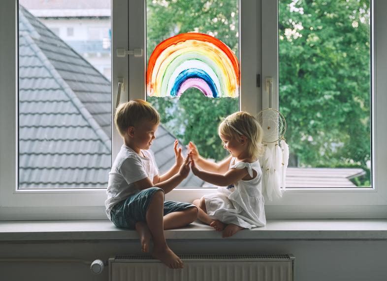 Enfants devant une fenêter avec la peinture d'un arc en ciel